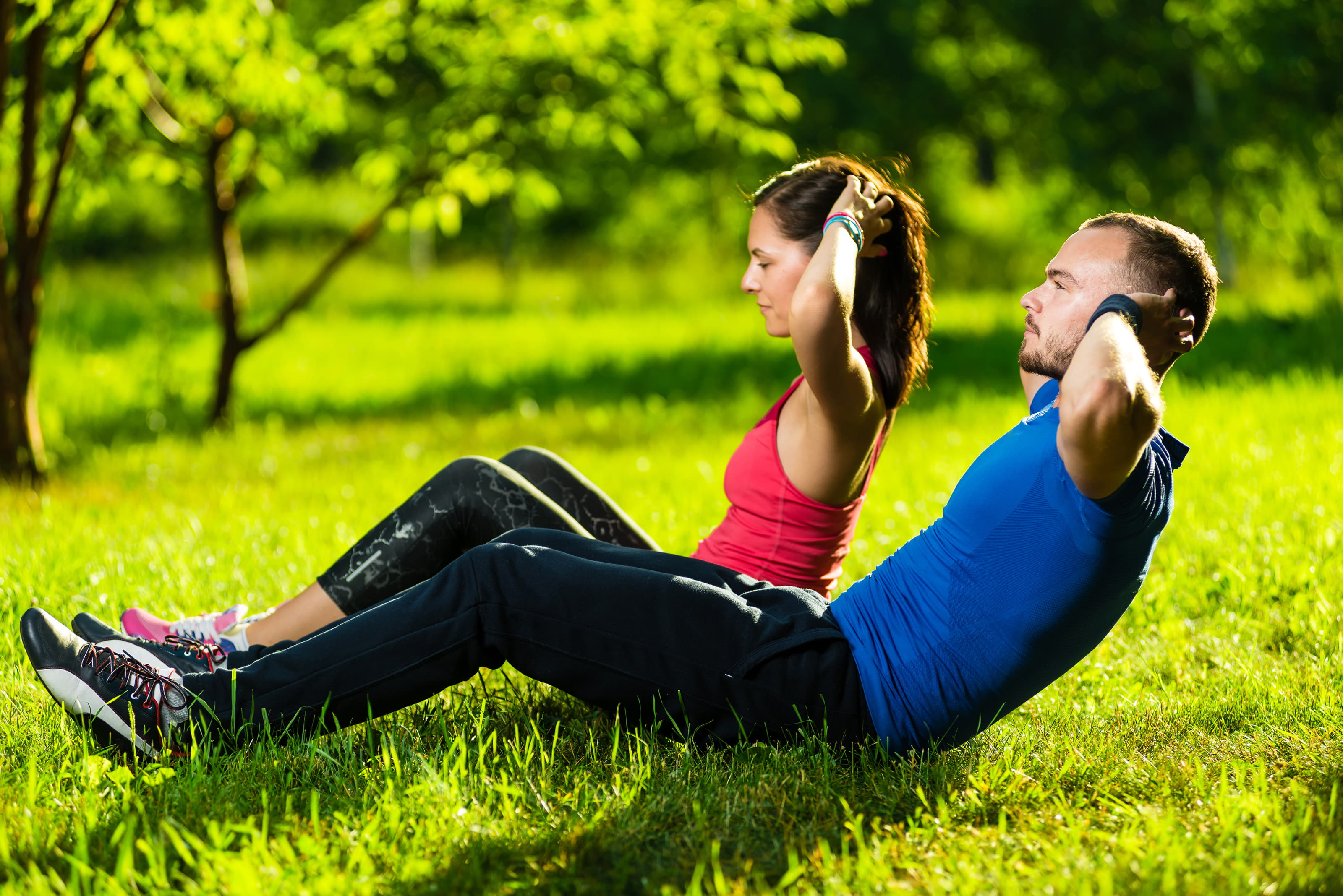 Two people exercising on grass in a park